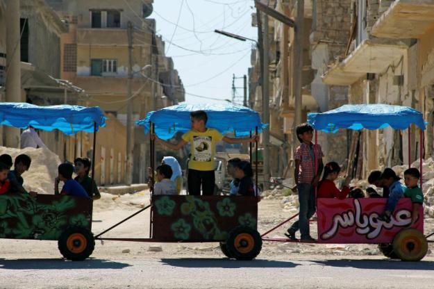 Children ride in carts on the third day of Eid al-Adha in the rebel controlled city of Idlib